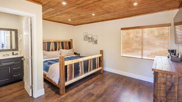 A bedroom with a wooden ceiling, a bed with a wooden frame, a dresser, and a window with blinds.