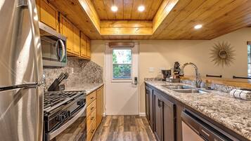 A kitchen with wooden cabinets, granite countertops, stainless steel appliances, and a wooden ceiling.