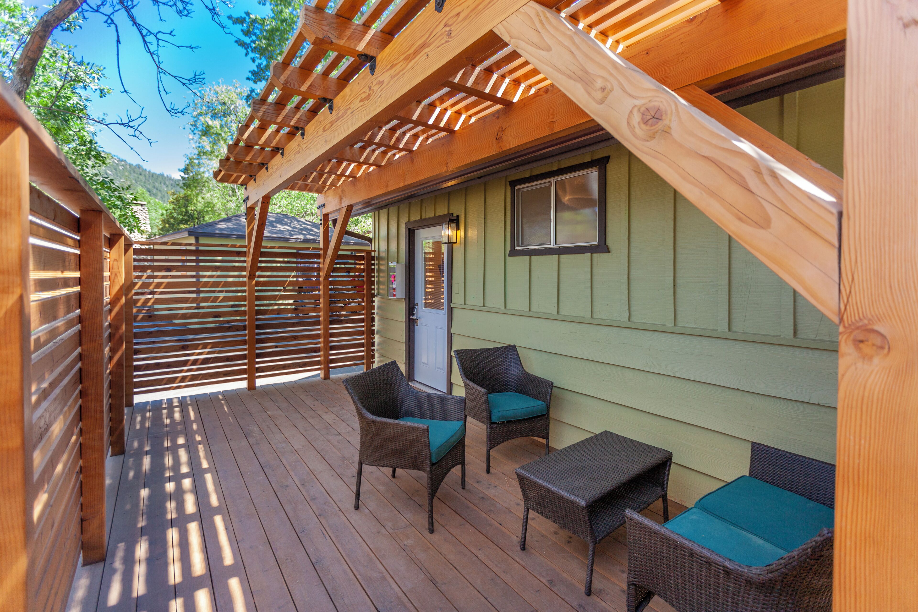 Une terrasse extérieure couverte, aménagée avec des meubles en osier et une pergola en bois.