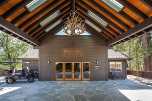 A lodge entrance with a stone-paved driveway, a golf cart, and a sign reading "Taquintz Pines Retreat". - Tahquitz Pines Retreat (Idyllwild)