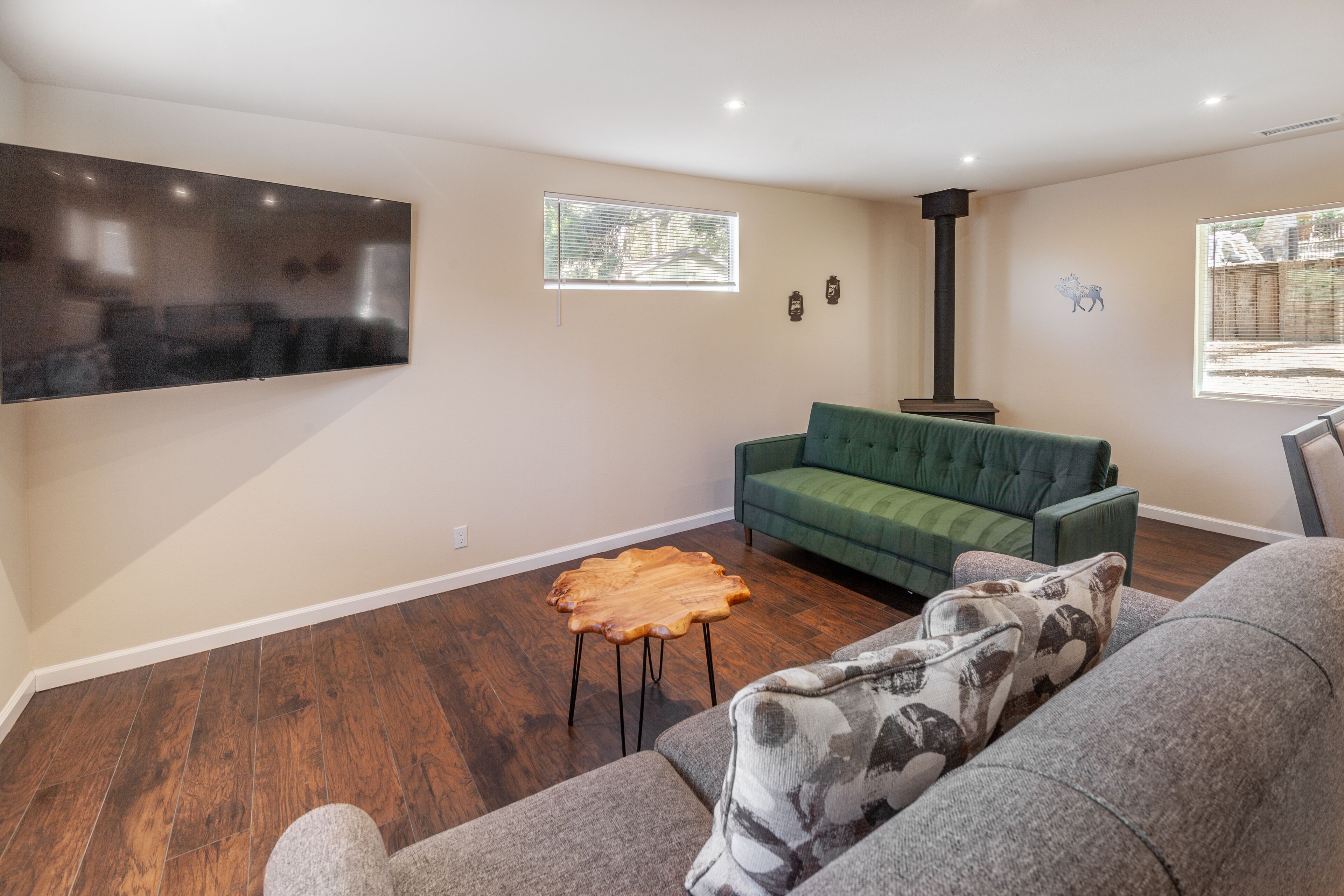 Ein Wohnzimmer mit Flachbildfernseher, einem grünen Sofa, einem Holztisch und einem Kamin.