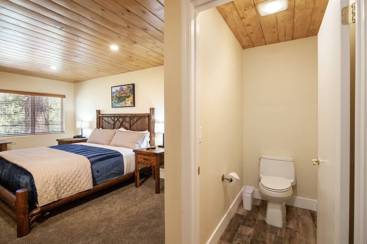 A bedroom with a wooden bed, a bedside table, and a window with blinds.