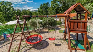 Un parque infantil de madera con columpios y una casita de juegos.