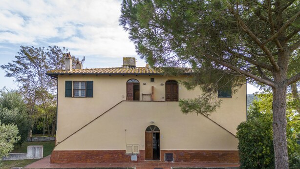 A two-story building with a beige facade, a red brick base, and a tiled roof. - Orbetello Giannella Apartment (Orbetello)