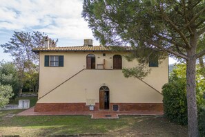 A two-story building with a beige facade, a red brick base, and a tiled roof. - Orbetello Giannella Apartment (Orbetello)