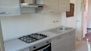 A kitchen with a gas stove, oven, and a stainless steel sink. - Orbetello Giannella Apartment (Orbetello)