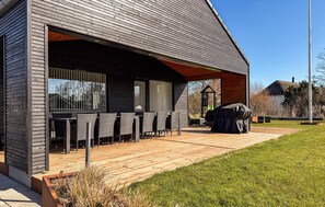 A modern building with a covered outdoor seating area, a barbecue grill, and a wooden deck. - 5 bedroom nice home in Hadsund (Hadsund)
