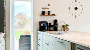 Eine moderne Küche mit Backofen, einer Kaffeemaschine und einer Uhr an der Wand.