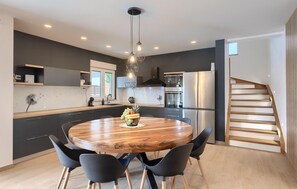 Una cocina moderna con una mesa redonda de madera, sillas negras y electrodomésticos de acero inoxidable.