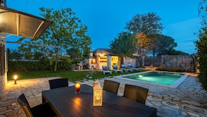 A stone patio with a pool, outdoor seating, and a stone building in the background.