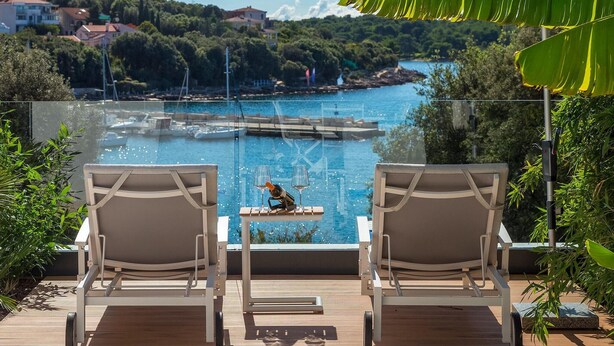 Two lounge chairs facing a pool with a view of a coastal area, including buildings and trees. - Gorgeous home in Pula (Pula)