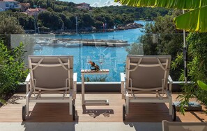 Two lounge chairs facing a pool with a view of a coastal area, including buildings and trees. - Gorgeous home in Pula (Pula)