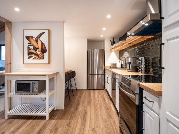 A modern kitchen with a stainless steel refrigerator, a microwave, and a wine rack.