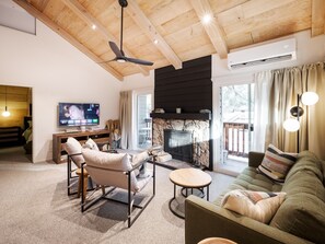 Un salon avec une cheminée, un téléviseur et un ventilateur de plafond.