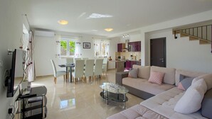 Un salon moderne comprenant un canapé, une table basse en verre et un coin repas avec des chaises et une table.