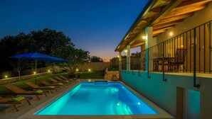 Une piscine avec des chaises longues et un espace patio couvert.