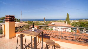 A terrace with a table and chairs, overlooking a coastal town and the sea. - Amazing home in Altavilla Milicia (Altavilla Milicia)