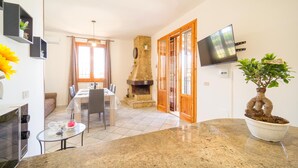 A modern kitchen with a stone fireplace, a dining area with a table and chairs, and a potted plant. - Amazing home in Altavilla Milicia (Altavilla Milicia)