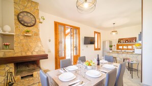 A dining area with a stone fireplace, wooden doors, and a kitchen with a stone countertop. - Amazing home in Altavilla Milicia (Altavilla Milicia)