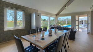 A spacious dining area with a glass table and black chairs, large windows, and a view of a swimming pool. - Stunning home in Pula (Pula)