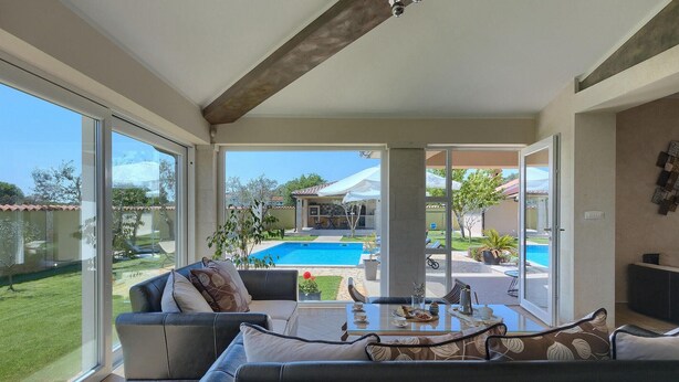 A spacious living area with a large sliding glass door leading to a pool and outdoor seating. - Stunning home in Pula (Pula)