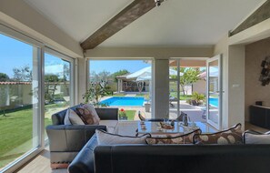 A spacious living area with a large sliding glass door leading to a pool and outdoor seating. - Stunning home in Pula (Pula)