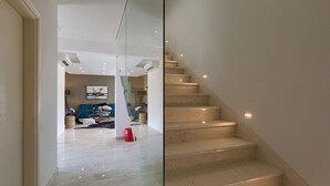 Un intérieur moderne avec un escalier, un espace de vie doté d’un canapé et une cloison en verre.