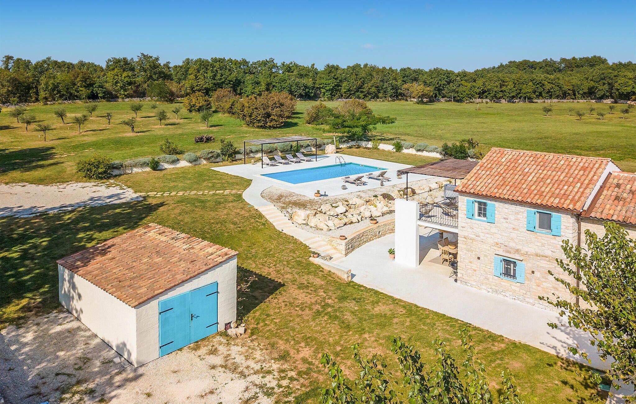 A villa with a swimming pool, stone walls, and a garden.