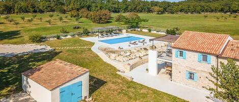 A villa with a swimming pool, stone walls, and a garden.