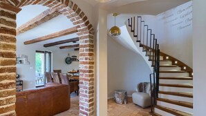 A modern interior with exposed brick walls, a wooden staircase, and a dining area with leather seating.