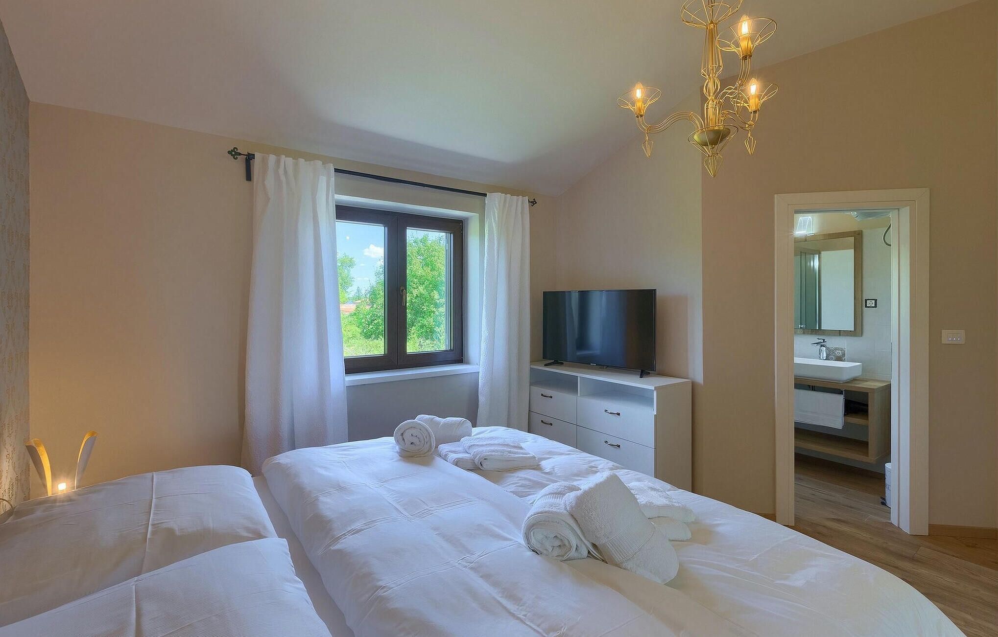 Una camera d'albergo con un letto, una televisione, un bagno e un lampadario.
