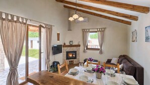 A cozy dining area with a wooden table set for four, a fireplace, and a sofa in the background. - Stunning home in Pula (Pula)