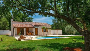 A two-story house with a swimming pool, a patio with lounge chairs, and a garden. - Stunning home in Pula (Pula)