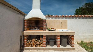 An outdoor brick oven with a chimney, a sink, and a tiled backsplash. - Stunning home in Pula (Pula)