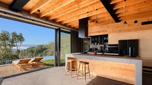 A modern kitchen with a large island, bar stools, and a view of the outdoors.