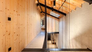 A modern interior with wooden walls, a mezzanine level, and a visible dining area.