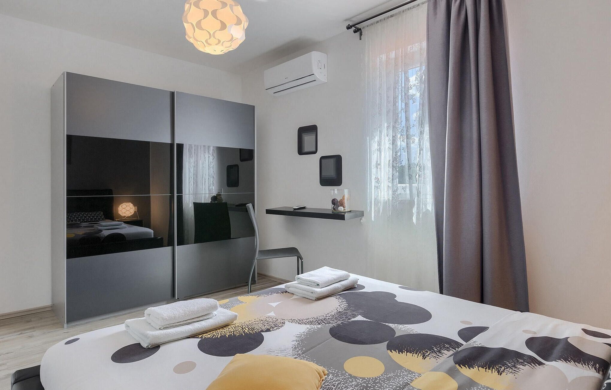Een moderne slaapkamer met een bed, een kledingkast, een nachtkastje en een raam met gordijnen.