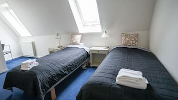 Une chambre double avec deux lits, un bureau, une chaise et des fenêtres de toit.