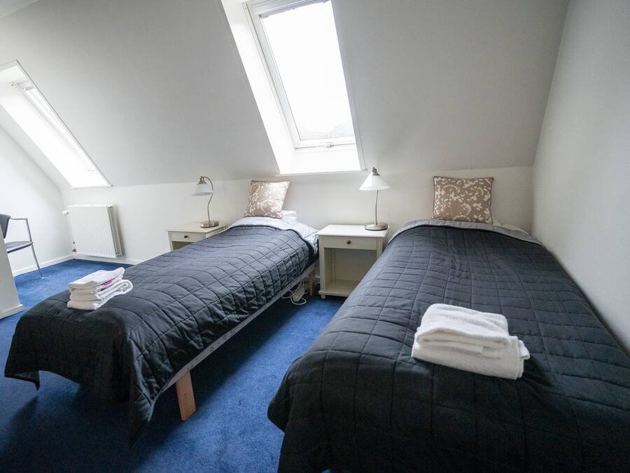 Une chambre double avec deux lits, un bureau, une chaise et des fenêtres de toit.