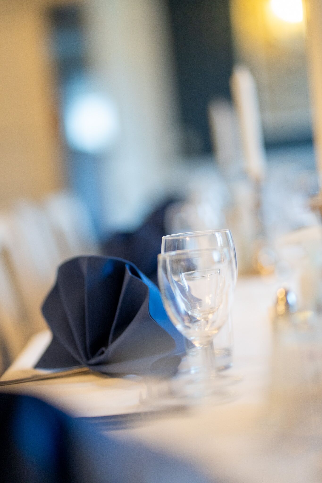 A dining table with a folded napkin, a clear glass, and a candle holder.