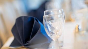 A dining table with a folded napkin, a clear glass, and a candle holder.
