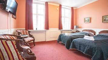 A hotel room with two beds, a TV, and a window with curtains.