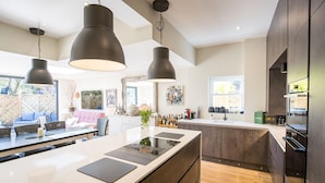 A modern kitchen with a large island, pendant lighting, and a view of the backyard.