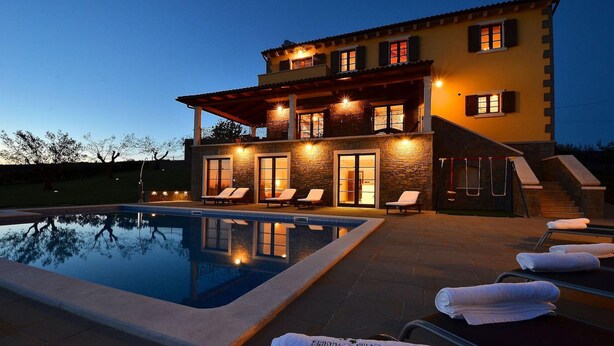Uma casa de dois andares com piscina, área de estar externa e escadaria que leva ao andar superior.