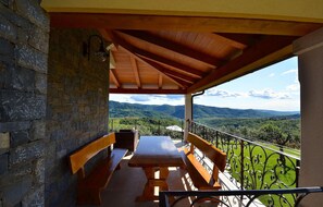 Relax in a serene outdoor space with a stone wall and rolling hills view, featuring a picnic table and benches.