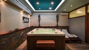 Um quarto de spa com uma banheira de hidromassagem grande, um banco de madeira e um claraboia no teto.
