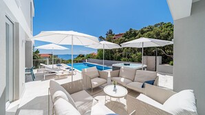 A modern outdoor patio with white furniture, a pool, and umbrellas. - Lovely home in Blato with sauna (Blato)
