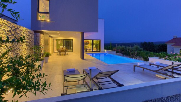 Een modern huis met een zwembad, terras en een zitgedeelte buiten.