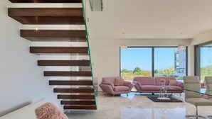 A modern interior with a staircase, two sofas, a coffee table, and a view through large windows. - Gorgeous home in Pula with sauna (Pula)