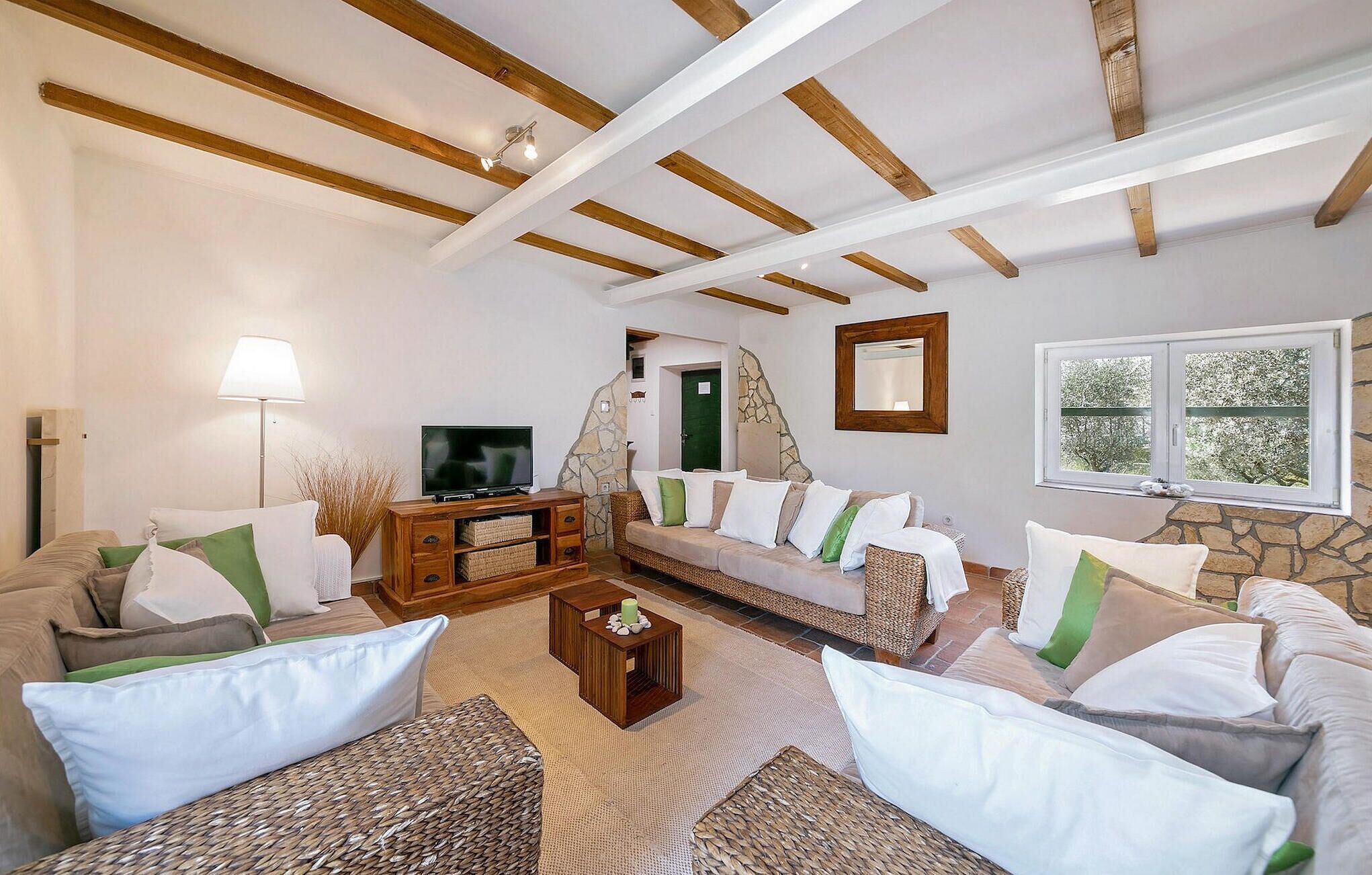 Sala de estar con un sofá, televisión, lámpara y pared de piedra.